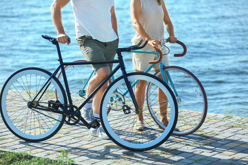 Mature couple with bicycles walking along river bank on summer day