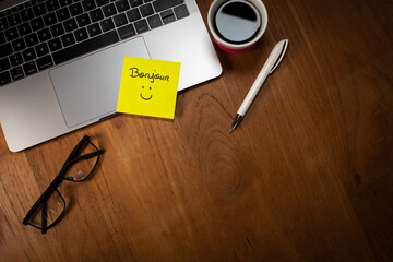 Illustration du bien-être et du bonheur au travail. Un papier autocollant est collé sur un ordinateur portable avec le mot bonjour et un sourire dessiné. © Tof - Photographie