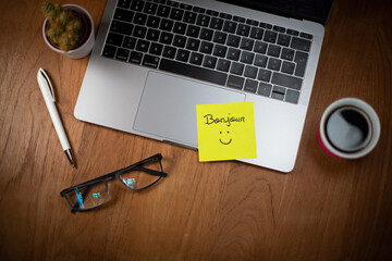 Illustration du bien-être et du bonheur au travail. Un papier autocollant est collé sur un ordinateur portable avec le mot bonjour et un sourire dessiné. © Tof - Photographie