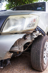 Fototapeta premium Destroyed car in car crash traffic accident on city road on city road. Smashed broken front auto headlight, dented hood without bumper in car accident. Auto life and health insurance. square.