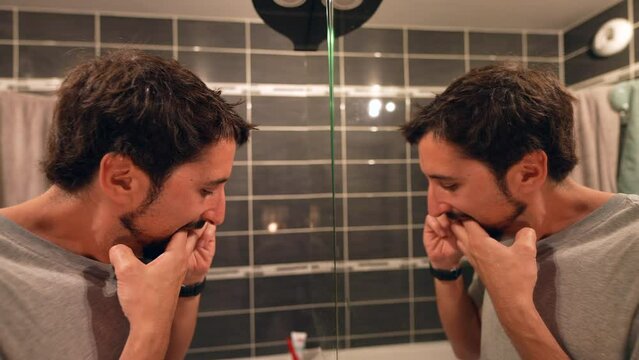 Person flossing teeth before bed man mirror reflection dental floss