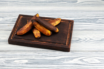 Fermented bananas on wooden board. Overripe brown fruits is suitable for baking tasty vegan banana bread