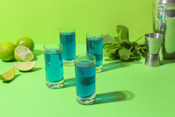 Shot cocktails, limes and mint on color background