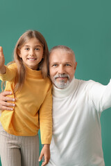 Little girl with her grandfather on green background