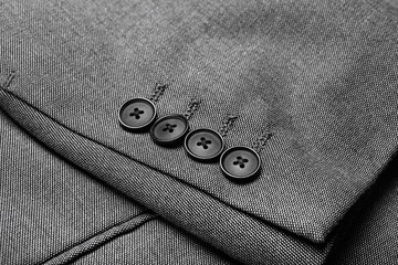 Sleeve of male jacket with black buttons, closeup