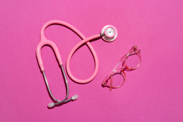 Stylish eyeglasses with stethoscope on pink background