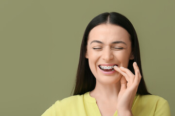 Beautiful woman with dental braces having pain on color background