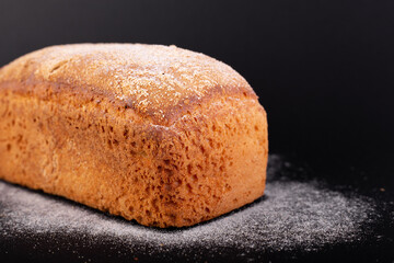 close up french lean bread with flour on a black background. Concept recipe of handmade bread