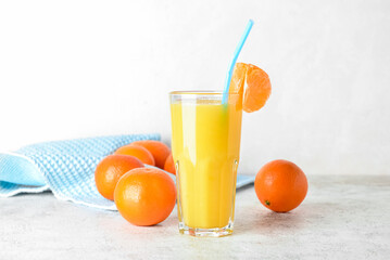 Glass of delicious tangerine juice and fresh fruits on light background