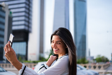Fototapeta premium Empowered young woman taking a selfie in financial district