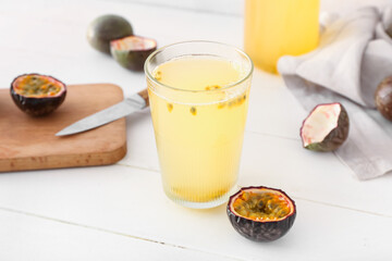 Glass of delicious passion fruit juice on light background