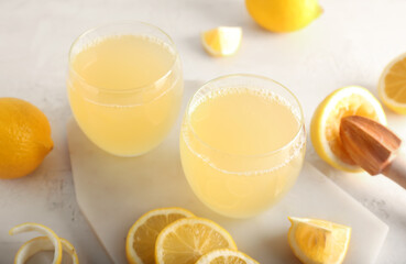 Fototapeta Board with glasses of fresh lemon juice on light background, closeup obraz