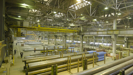 Yellow Indoor Crane. Work hanging of a crane at the plant for the production of pipes
