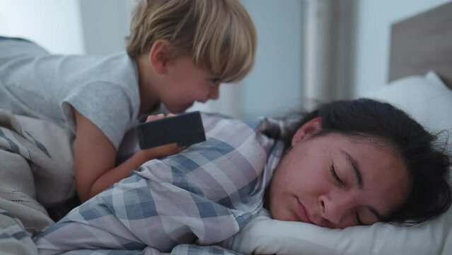 Child Waking Up Mother In Morning Bed Jumping On Top Mom