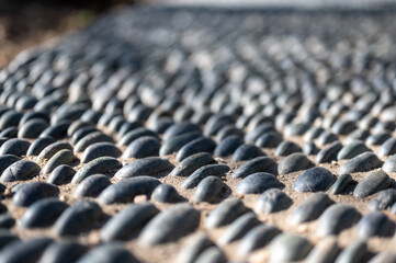 Selective focus on decorative pattern of river rocks laid in garden footpath. 