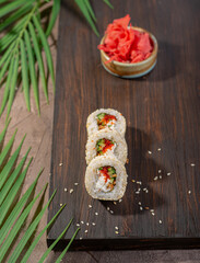 Fresh colorful uramaki on gray dish among palm tree