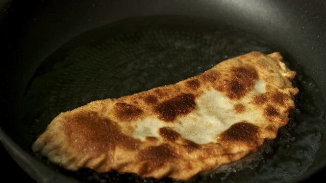 Process with fried homemade chebureks or qutab or calzone with minced meat and onion. Azerbaijani, Tatar, Caucasian, Greek cuisine.