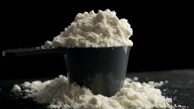Circular motion of scoop with protein powder on black background.