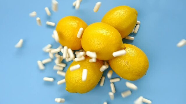 Vitamin C tablets. Flying vitamin C white pills and yellow lemons on a blue background.Natural Fruit Vitamin C. Health and medicine concept. 4k footage