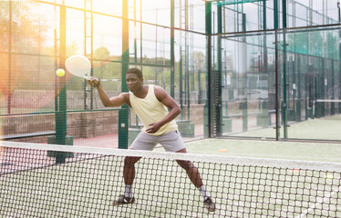 Obraz premium Portrait of young man enjoying popular racket sport padel, playing with friends on court outdoor