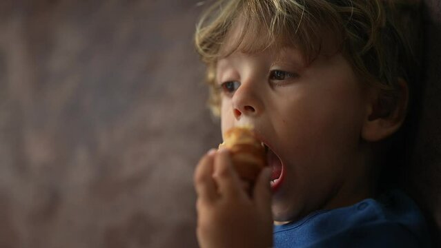 Child eating croissant  kid eats snack one little boy eats food
