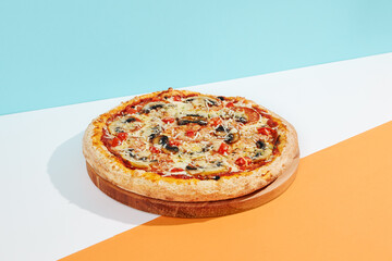 Italian pizza with mushroom and cheese on coloured background. Vegan pizza with mushroom and tomato in minimal style on blue and orange color. American pizza delivery concept with color backdrop