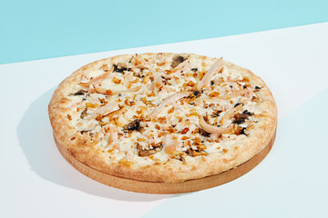 Italian pizza with mushrooms and creamy sauce on coloured background. Mushroom pizza with cheese in minimal style on light blue color. American pizza delivery concept with color backdrop.