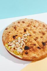 Italian closed pizza with cheese, potatoes and chicken on coloured background. Chicken pie with cheese and potatoes in minimal style. American pizza delivery concept with color backdrop.