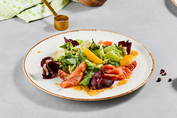 Healthy food - salmon salad with vegetables, greens and citrus. Summer salad with salmon, beetroot, orange and citrus dressing on concrete background. Summer menu in minimal style. Aesthetic food.