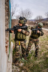 Two men soldiers in uniform braking in to the house ruin during mission battle operation dogs of war volunteers mercenaries contractor secure the building armed service holding rifles pointed