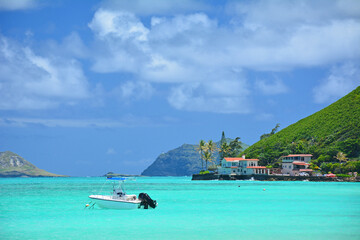 Obraz premium Boat anchored in calm, turquoise waters on a clear sunny day at Lanikai Beach on the windward side of Oahu, Hawaii. 