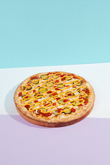 Italian pizza with chicken and pickled cucumber on coloured background. Cheese pizza with chicken in minimal style on purple and blue colours. American pizza delivery concept with color backdrop