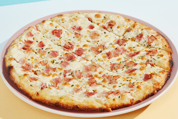 Italian pizza with bacon and cheese on coloured background. Cheese focaccia with bacon in minimal style on blue colour. American pizza delivery concept with color backdrop