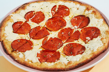 Italian pizza with pepperoni and cheese on coloured background. Cheese focaccia with salami in minimal style on blue and orange color. American pizza delivery concept with color backdrop