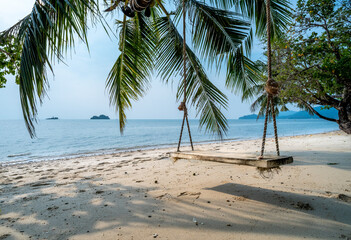 White sandy beach and a wooden swing at Koh Chang island in Thailand
