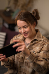 A pretty girl is holding a portable game console in her hands. Close-up. Video games, virtual reality, esports, cyberspace, entertainment, game strategy, modern technologies.