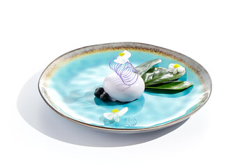 Blackberry mousse cake for concept design. Blueberry souffle with mirror glaze on ceramic plate. Mini cake with blackberry in restaurant menu. Summer sweet dessert - berries mousse with flowers.