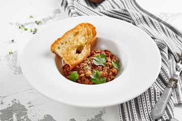 Georgian lobio in white plate with bread. Traditional georgian dish from red bean in sauce and spices.  Vegetarian appetizer from georgian cuisine. Caucasus lobio in restaurant menu. Vegan food.