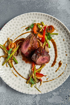 Roasted Beef fillet with vegetables. Roasted Mignon steak with paprika and celery. Beef tenderloin with garnish. Beef steak medium rare doneness. Delicious meat menu. Dish concept with angus beef.
