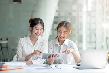 Two asian business woman work together to get the job done at the office.