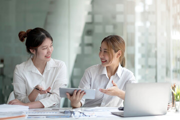 Two asian business woman work together to get the job done at the office.