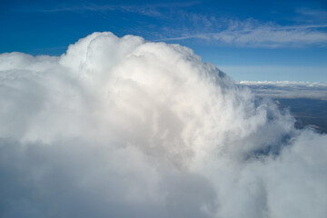 Aerial view from airplane window at high altitude of earth covered with puffy cumulus clouds...