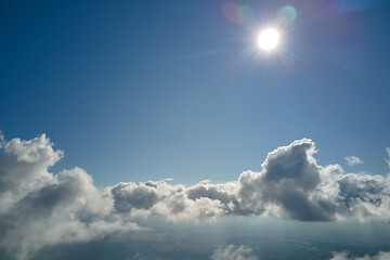 Aerial view from airplane window at high altitude of earth covered with white puffy cumulus clouds