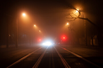 Night deserted street in heavy fog. blurry lights of passing cars.