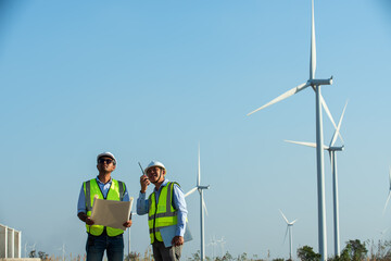couple standing in front of windmill. workers in the wind.  two engineers discussing against...