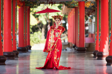 woman in traditional costume. Beautiful young woman in a bright red dress and a crown of Chinese...