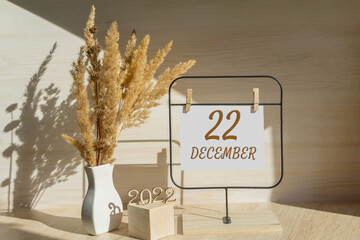 december 22. 22th day of month, calendar date. White vase with dead wood next to the numbers 2022 and stand with an empty sheet of paper on table. Concept of day of year, time planner, winter month