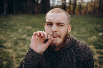 Young man beard smokes cigarette or tobacco. Guy is addicted to cigarettes and always smokes lot of...