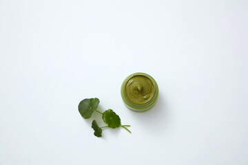 Top view of gotu kola decorated with cream and cotton pad in white background 