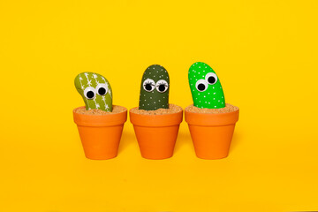Three painted rocks in shades of green with plastic googly eyes that give a playful and whimsical...